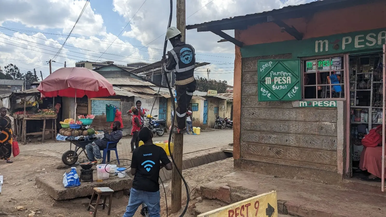 A konnekt technician installs street Wi-Fi equipment on a pole above a busy road