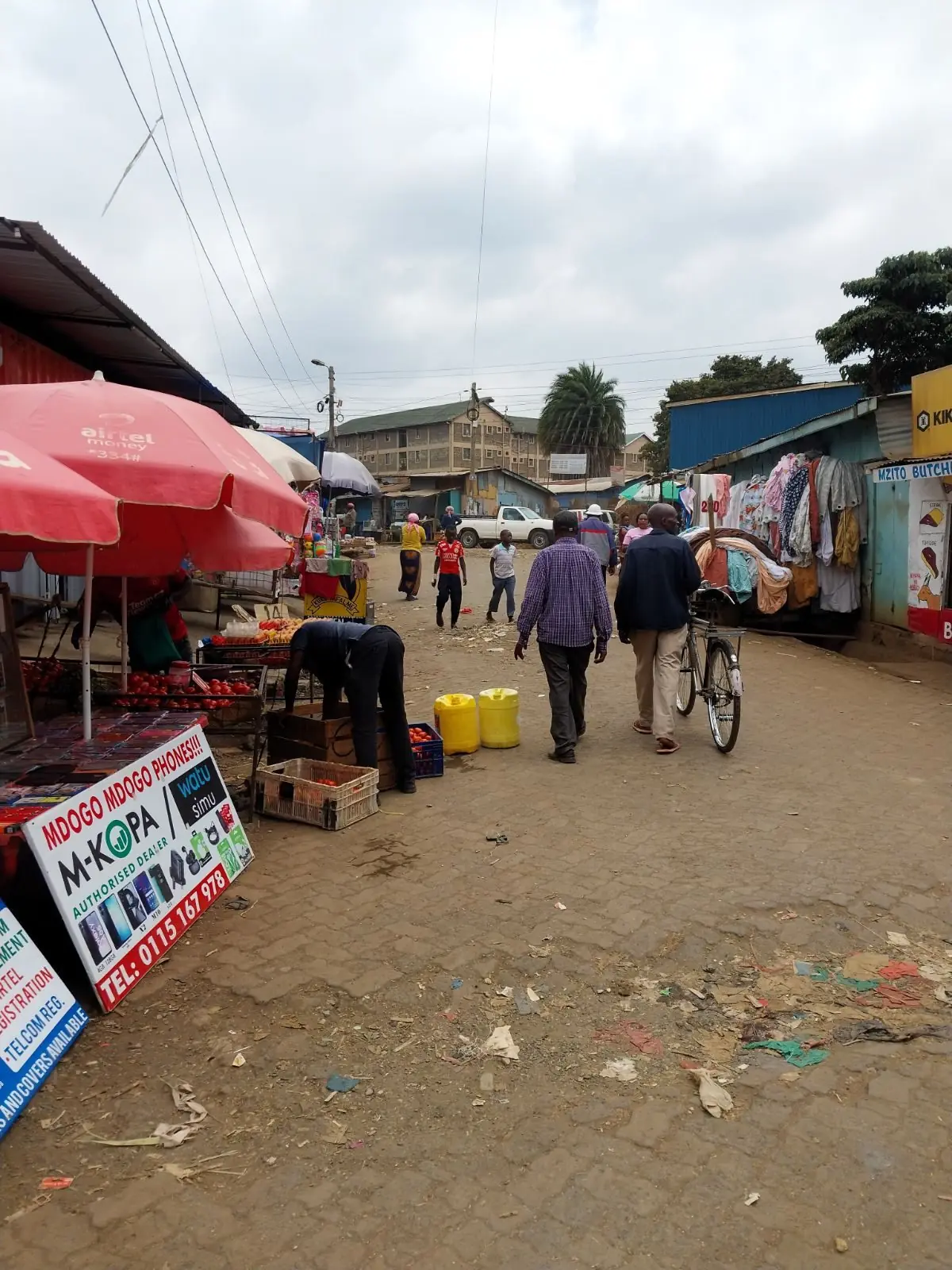 A dense Nairobi street with overhead cabling, boda bodas and shoppers